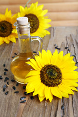 Sunflowers with seeds and oil on wooden background