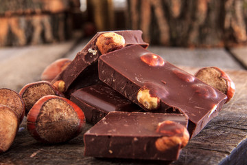 stack of chocolate pieces with hazelnuts on wooden table