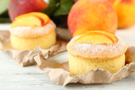 Tasty mini cakes with fresh peach, on wooden table