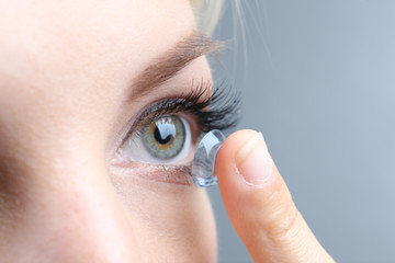 Medicine and vision concept - young woman with contact lens, - obrazy, fototapety, plakaty