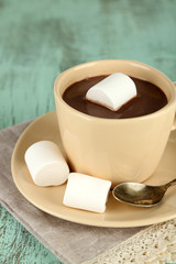 Hot chocolate with marshmallows in mug, on wooden background