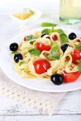 Spaghetti with tomatoes, olives and basil leaves