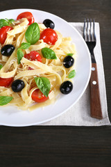 Spaghetti with tomatoes, olives and basil leaves