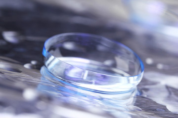 Contact lens with water drops on bright background