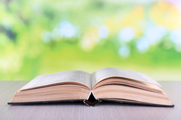 Open book on wooden table on natural background