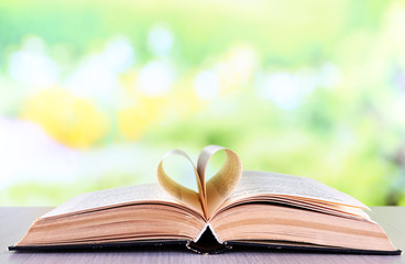 Open book on wooden table on natural background