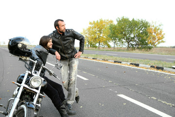 Two bikers near motorcycle on road