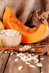 Pumpkins and pumpkin seeds in bowl on wooden background