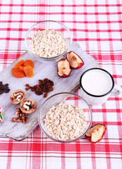 Bowl of oatmeal, mug of yogurt, marmalade, chocolate, raisins,