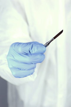 Surgeon's hand holding scalpel closeup