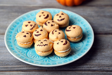 Tasty Halloween macaroons on plate, on wooden table