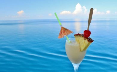 A tropical drink on a cruise ship rail with ocean in the backgro