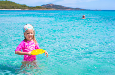 Little girl playing frisbee during tropical vacation in the sea