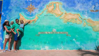 Family of four near big map of Caribbean island Turks and Caicos