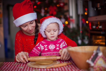 Little girl with young mother baking Christmas gingerbread