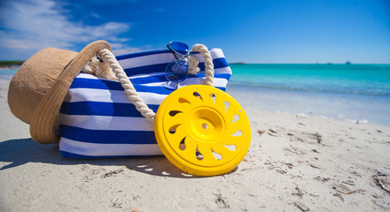 Stripe bag, straw hat, sunblock and frisbee on white sandy