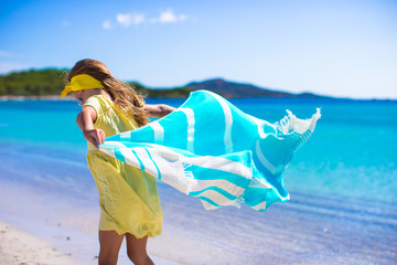 Little girl have fun with beach towel during tropical vacation