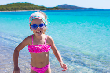 Adorable little girl have fun in shallow water at tropical beach
