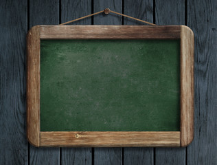 Old green menu blackboard hanging on wooden wall