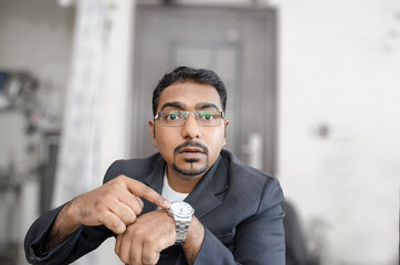 indian businessman with french beard pointing at wrist watch