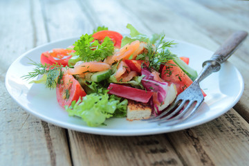Plate with salad with salmon, fresh vegetables and herbs