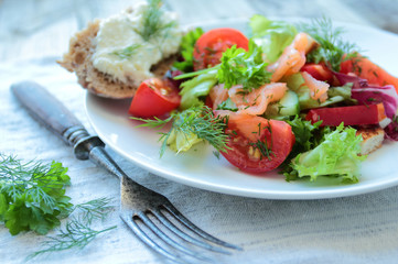 Fresh salad with salmon and vegetables on white plate