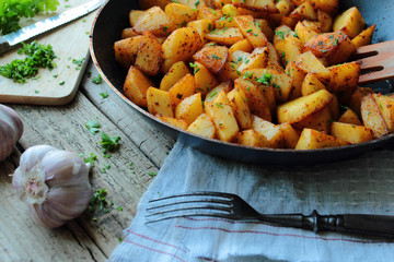 Fried potatoes chips on a pan with fresh herbs
