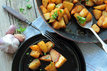 Pan and plate with fried potatoes with herbs