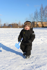 Fototapeta na wymiar lovely 2 years toddler walking with shovel in winter