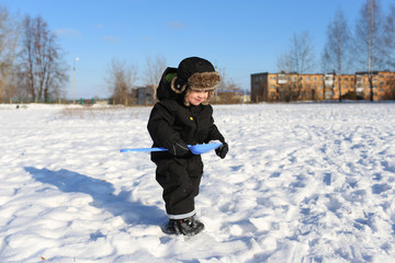 Fototapeta na wymiar 2 years little boy walking with shovel in winter