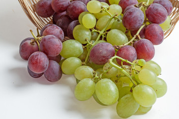 Raisin blanc et rose dans une corbeille sur fond blanc