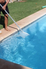 Mann reinigt Swimmingpool mit Netz im Urlaub