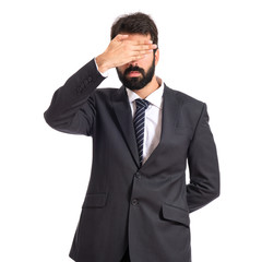 Businessman covering his eyes over isolated white background