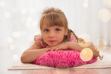 Cute little girl enjoying lying on the floor at home. Holiday li