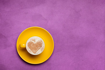 Cup of coffee with heart shape symbol on color background.