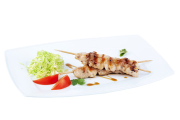 chicken kebab with cabbage and tomatoes on a square plate