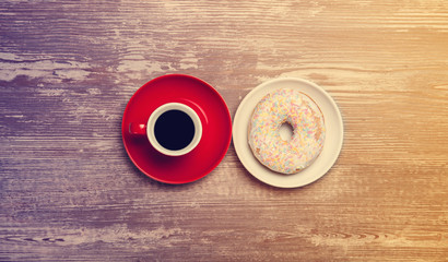 Cup of coffee and donut on a table.
