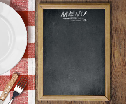 Menu blackboard top view on table with dish, knife and fork