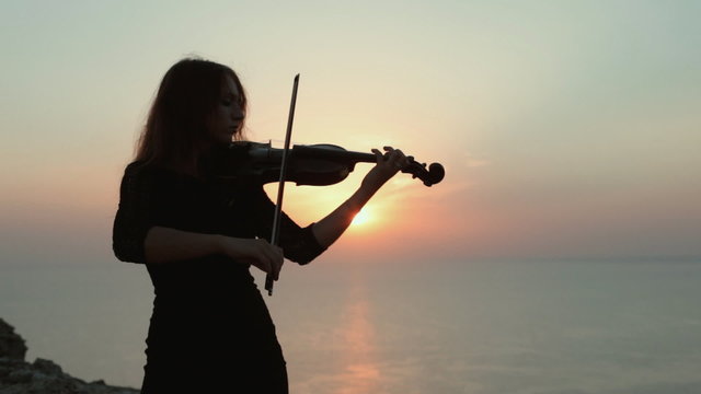 Violinist on the background of an incredibly beautiful sunset on