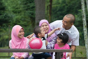 Happy Malay Asian Family enjoying family time together in the pa