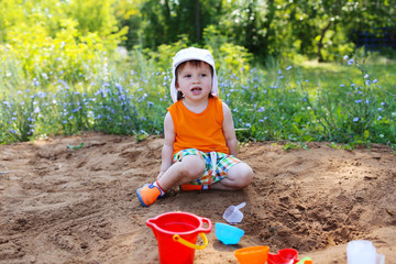 lovely little boy playing with sand on playground