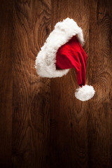 Obraz na płótnie Canvas Santa hat hanging on a wooden surface