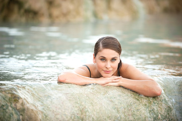 Pretty young woman takes a bath in the natural thermal waters of