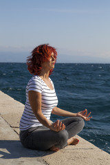 Fototapeta na wymiar Woman performing joga on sea coast, on windy sunny day
