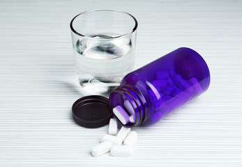 Pills in bottle on white table
