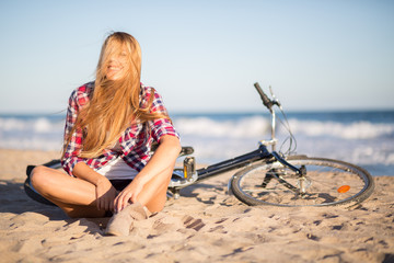 Fototapeta na wymiar girl sitting next to bike on the beach
