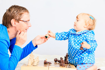 little daughter playing chess with father