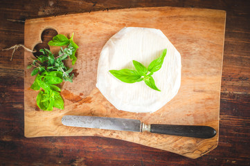 Smelly blue cheese on a wooden rustic table with knife and basil