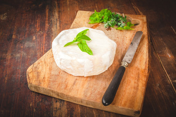 Smelly blue cheese on a wooden rustic table with knife and basil