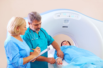 medical staff preparing patient to CT scanner procedure